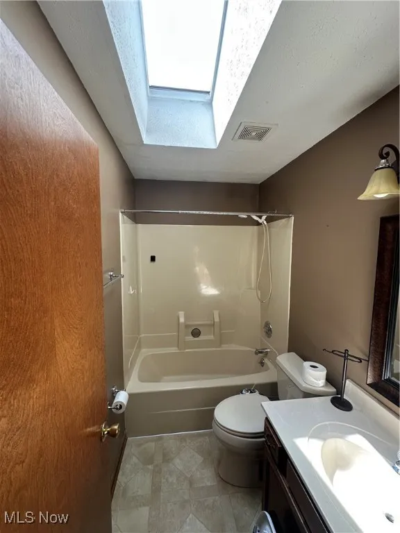 Bathroom featuring a skylight, vanity, washtub / shower combination, and tile patterned floors