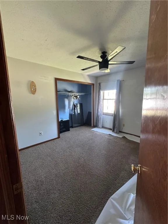 Bedroom with a textured ceiling, carpet flooring, and a ceiling fan