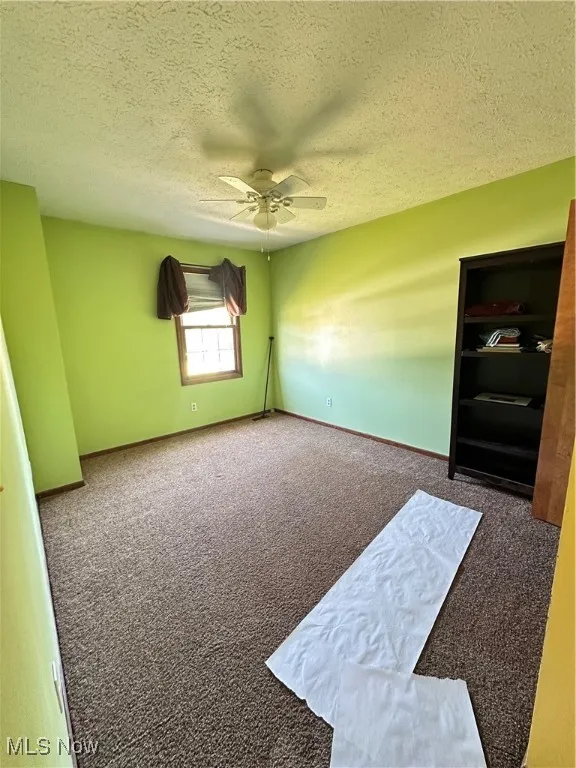 Bedroom featuring carpet flooring, a textured ceiling, and ceiling fan