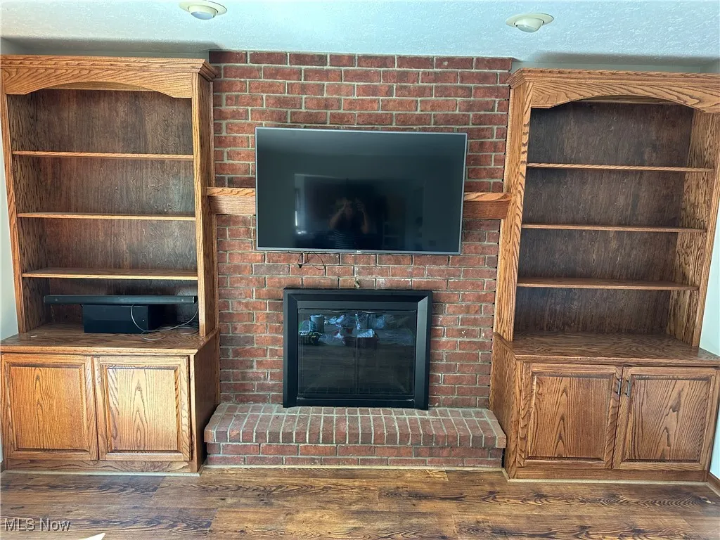 living room with wood finished floors, built in shelves and a fireplace