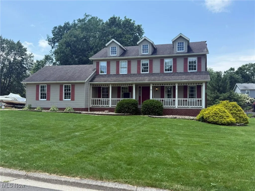 Colonial inspired home with a porch, a front lawn, and roof with shingles