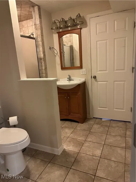 Full bathroom in basement featuring vanity, tile patterned floors, and a shower