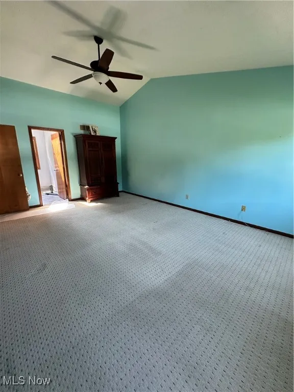 Primary bedroom featuring carpet flooring, vaulted ceiling, and ceiling fan