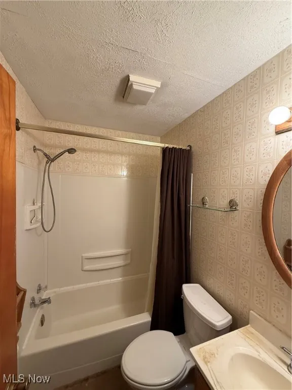 Full bath featuring shower / tub combo, a textured ceiling, and vanity