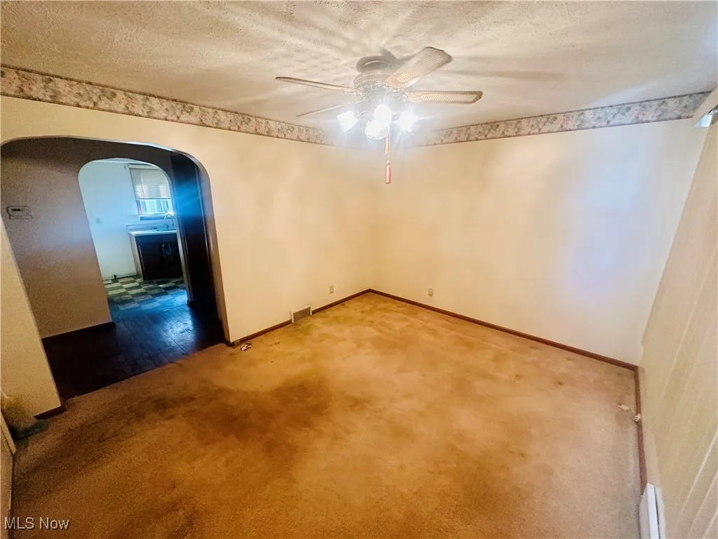 Unfurnished room with ceiling fan, a textured ceiling, and carpet