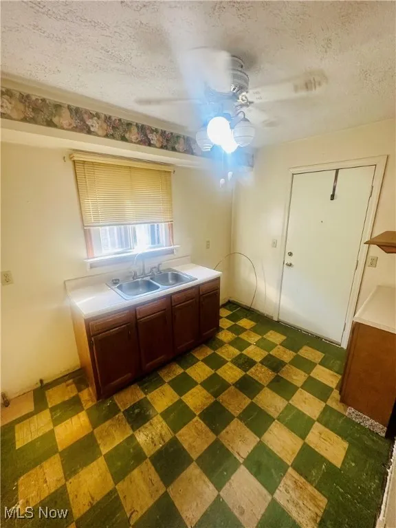 Kitchen with ceiling fan, sink, and a textured ceiling