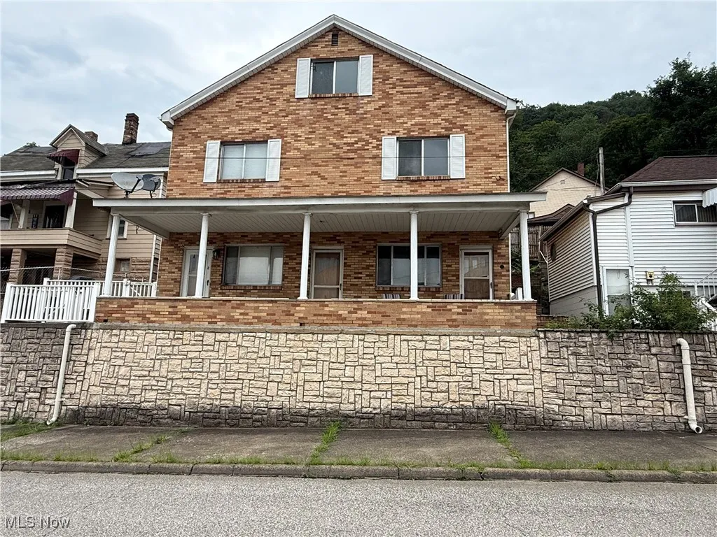 View of front facade with brick siding and a porch