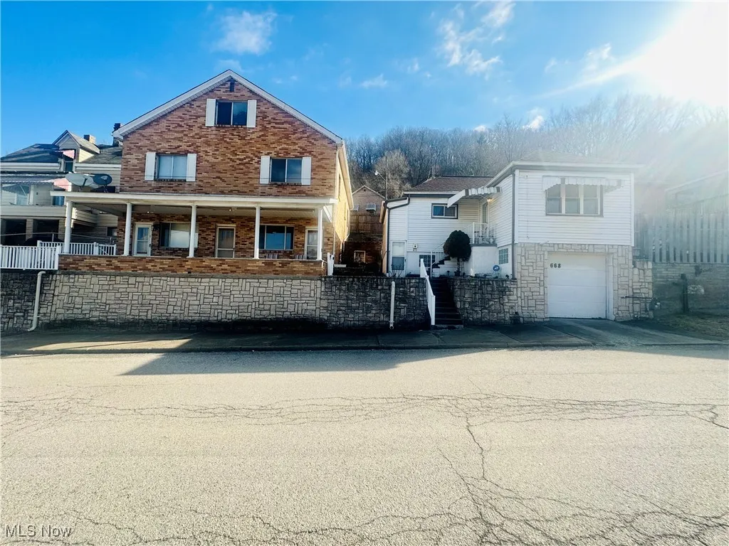 View of front of house with stairs, concrete driveway, a garage, and stone siding