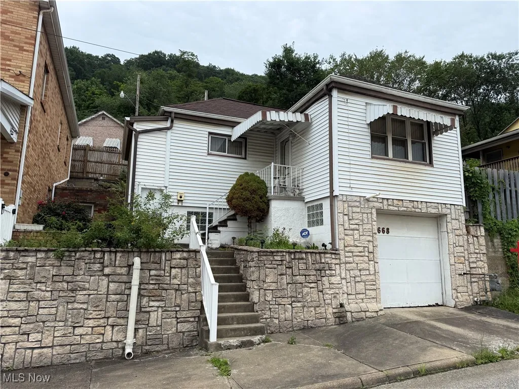 View of front of house with stairs, concrete driveway, a garage, and stone siding