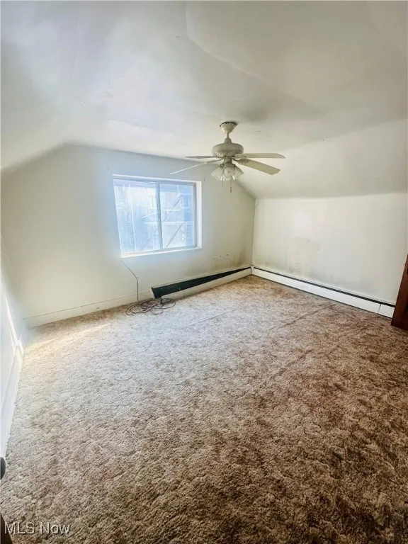 Additional living space with ceiling fan, a baseboard radiator, lofted ceiling, and carpet
