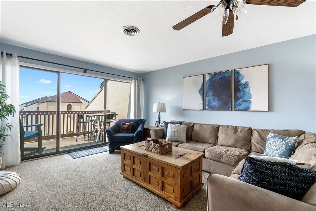 Carpeted living area with ceiling fan