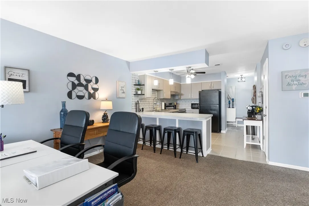 Office area featuring a ceiling fan, light carpet, and light tile patterned floors
