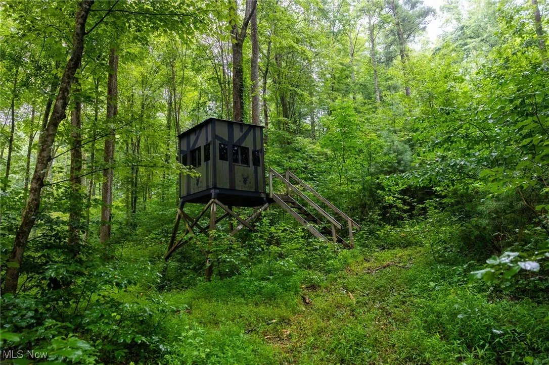 View of outdoor structure featuring a wooded view and stairway