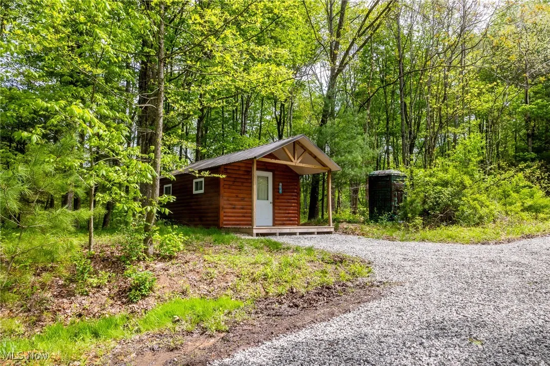 View of outbuilding featuring gravel driveway and a forest view