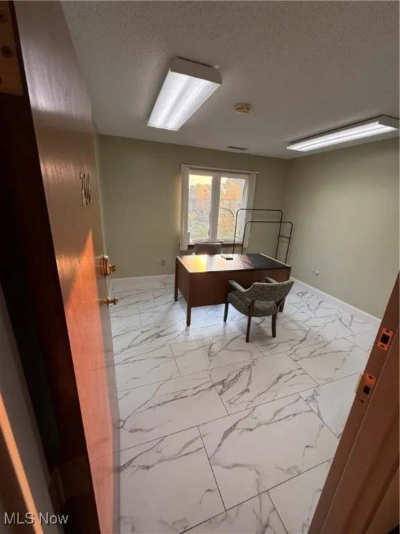 Office area with marble finish floors and a textured ceiling