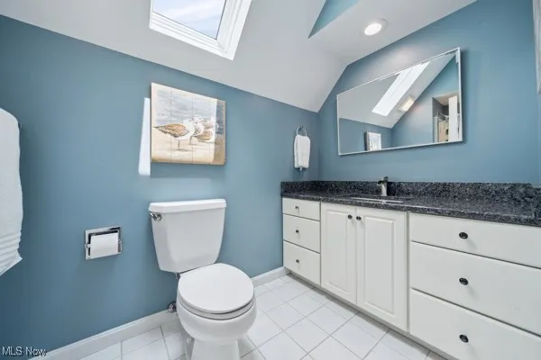 Bathroom with lofted ceiling, vanity, a skylight, and tile patterned floors