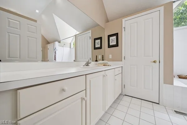 Bathroom with lofted ceiling, vanity, tile patterned floors, a shower, and a tub