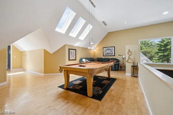 Recreation room featuring billiards table, vaulted ceiling, a skylight, and light wood-style flooring
