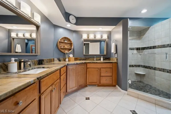 Bathroom with double vanity, a stall shower, tile patterned flooring, and recessed lighting