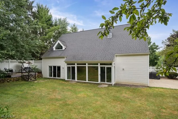 Back of house with a deck and a shingled roof