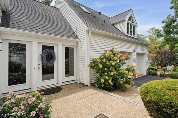 View of side of property with a shingled roof and a garage