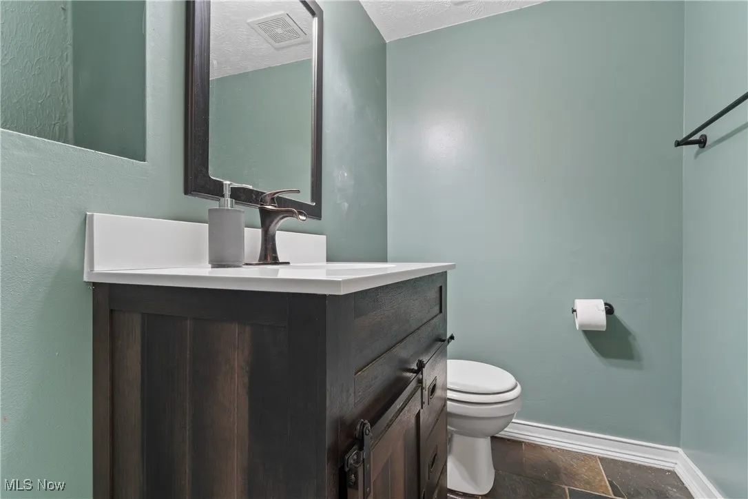 Bathroom featuring vanity, stone finish flooring, and a textured ceiling