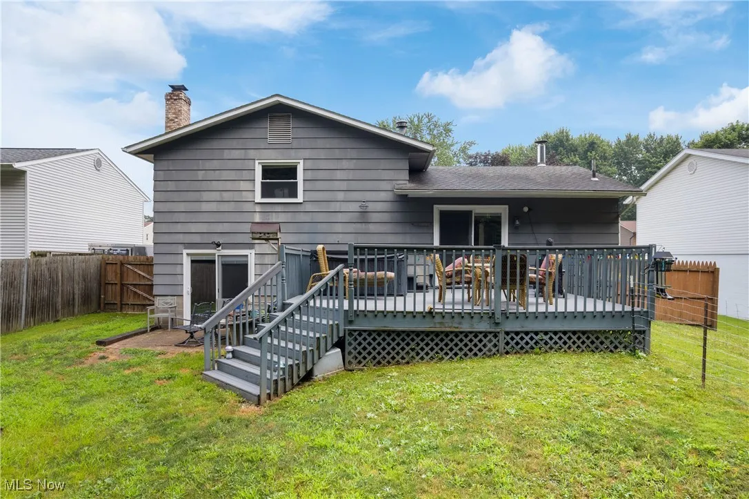 Back of property with a fenced backyard, a wooden deck, and a chimney