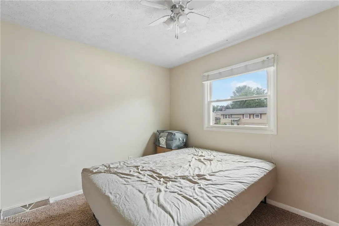 Carpeted bedroom featuring a textured ceiling and a ceiling fan