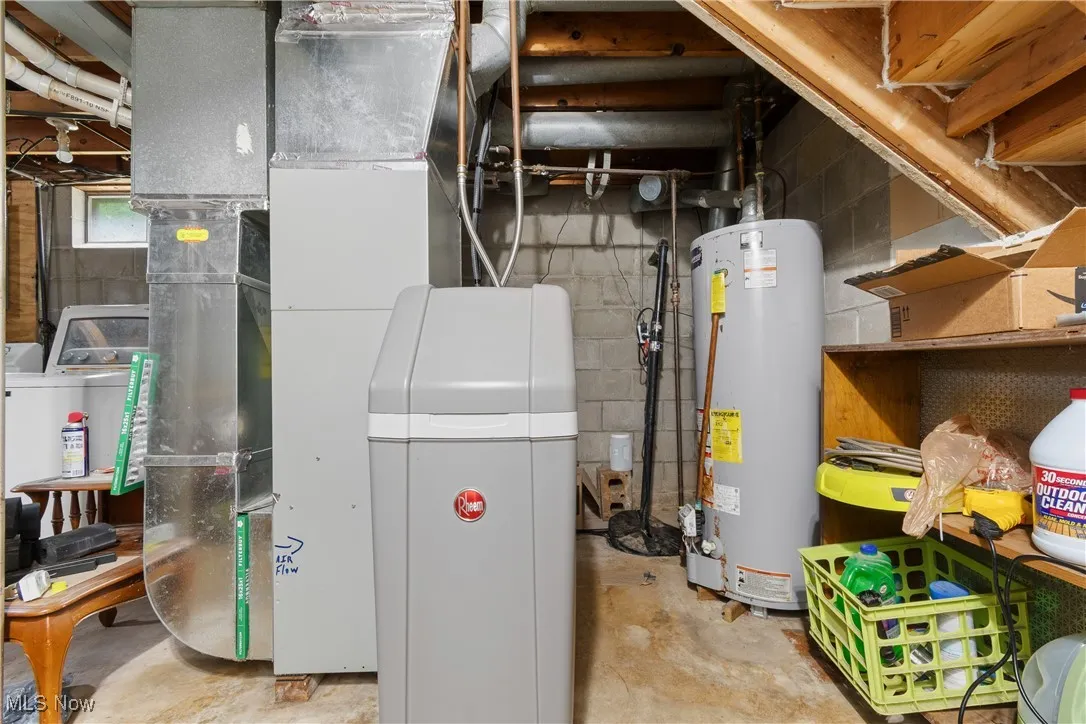 Utility room featuring water heater, heating unit, washer / clothes dryer, and drainage system