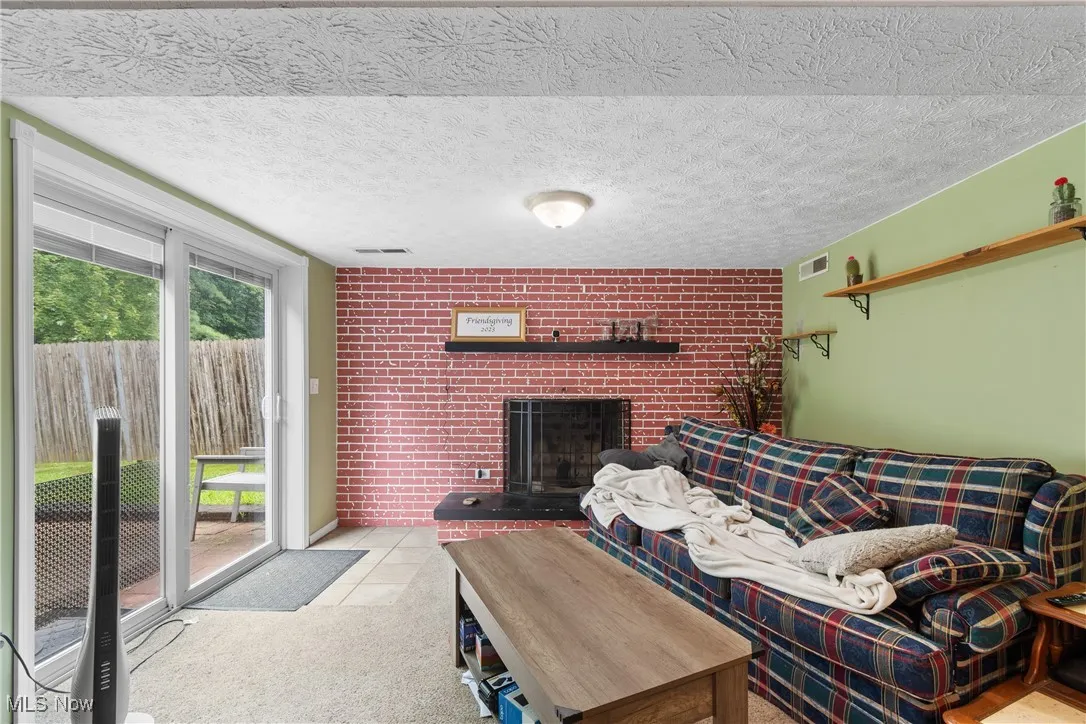Living area featuring a brick fireplace, carpet flooring, and brick wall
