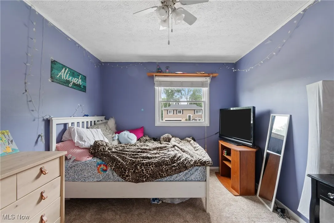 Carpeted bedroom featuring a textured ceiling and ceiling fan