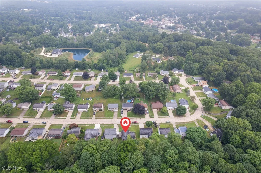 View of property location featuring a heavily wooded area and nearby suburban area