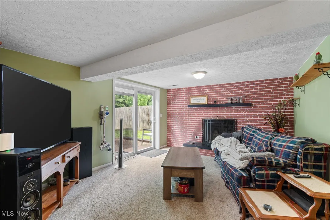 Carpeted living room featuring a fireplace and a textured ceiling