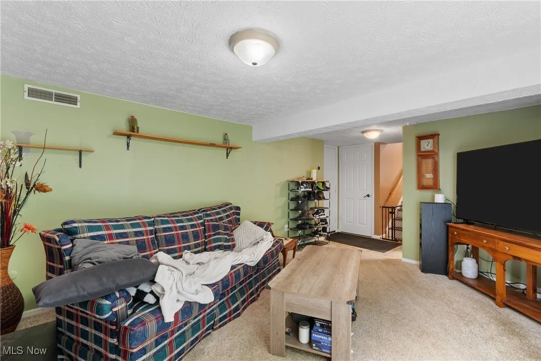Carpeted living room featuring a textured ceiling and baseboards