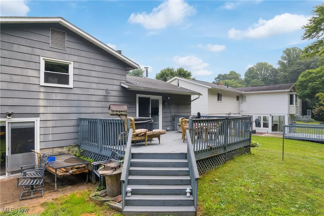 Back of property featuring a lawn and a wooden deck