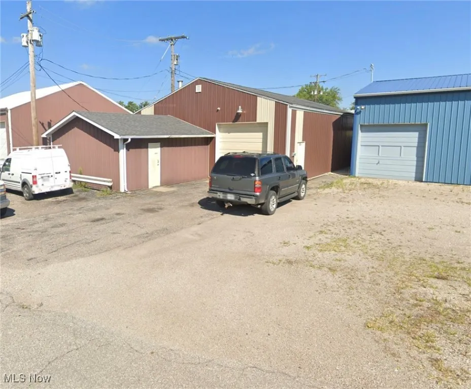 View of front of house featuring an outdoor structure, a garage, and a metal roof