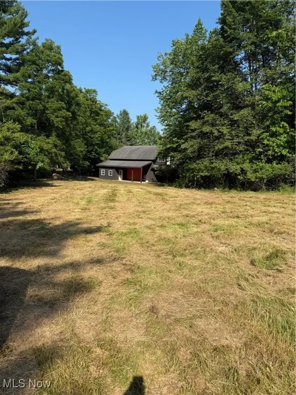 View of grassy yard with a view of trees