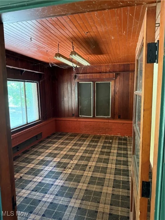 Spare room featuring wooden ceiling and wooden walls