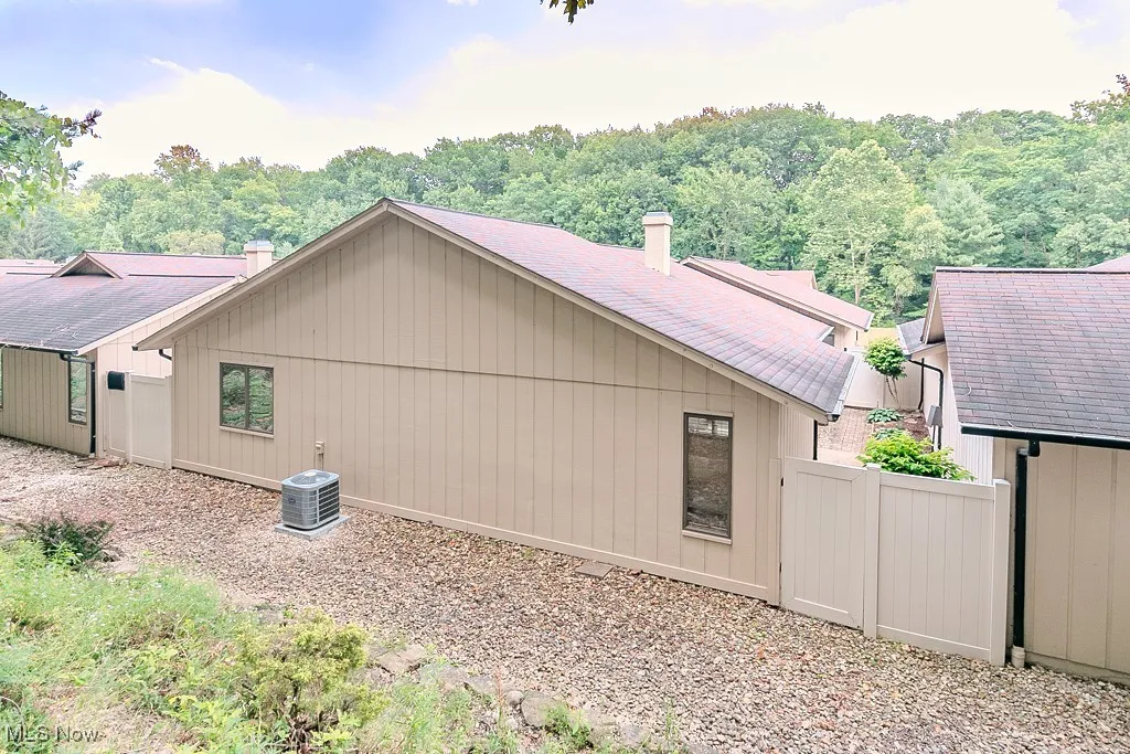 View of side of property with a chimney, roof with shingles, and a forest view