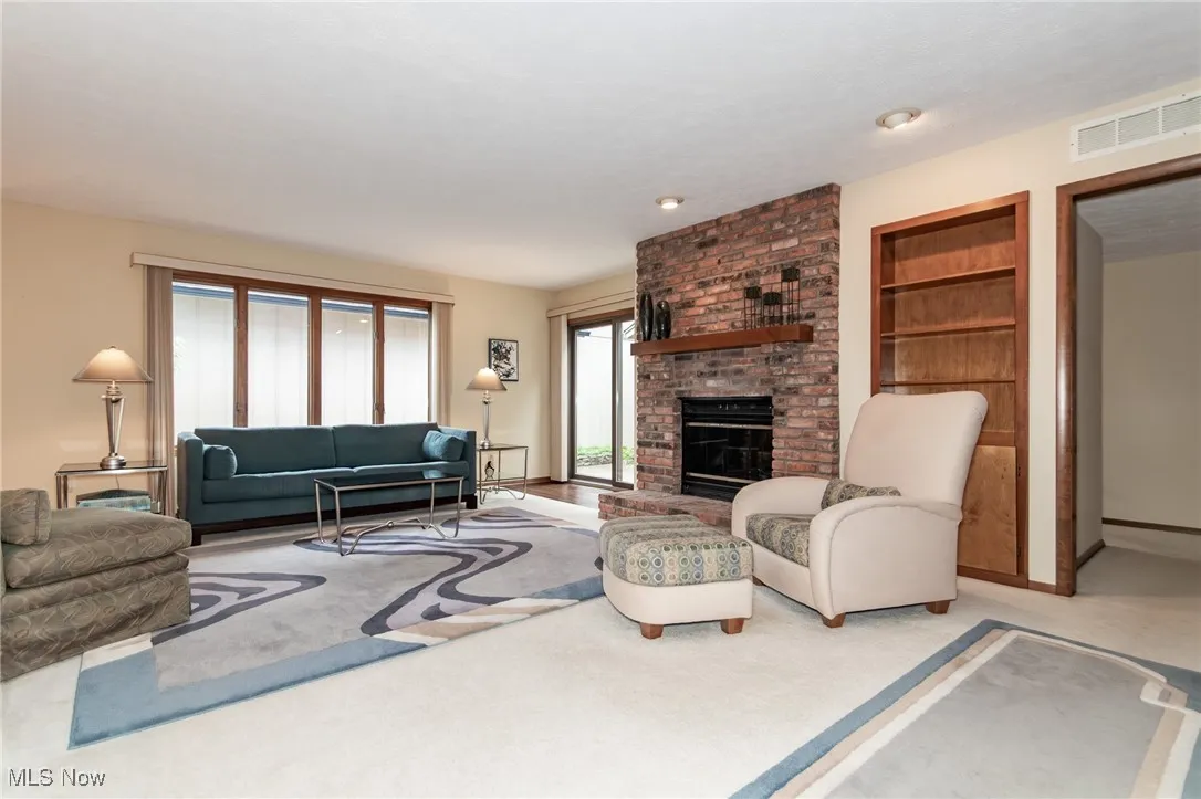Living room with a fireplace, light carpet, and built in features