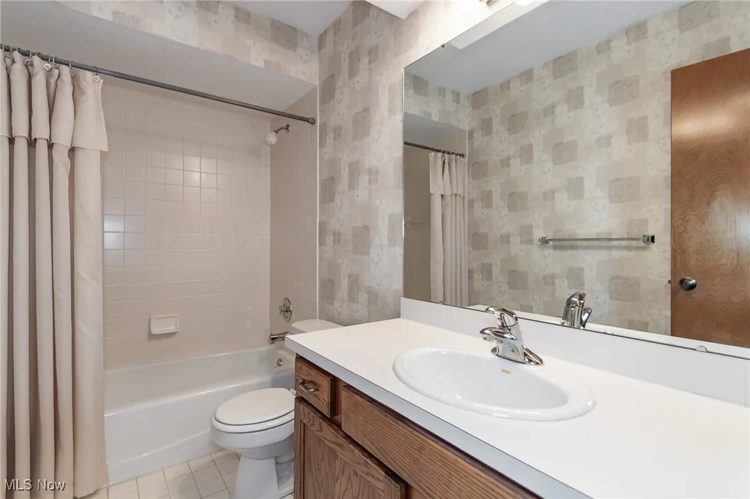 Bathroom with vanity, shower / bath combination with curtain, and tile patterned floors