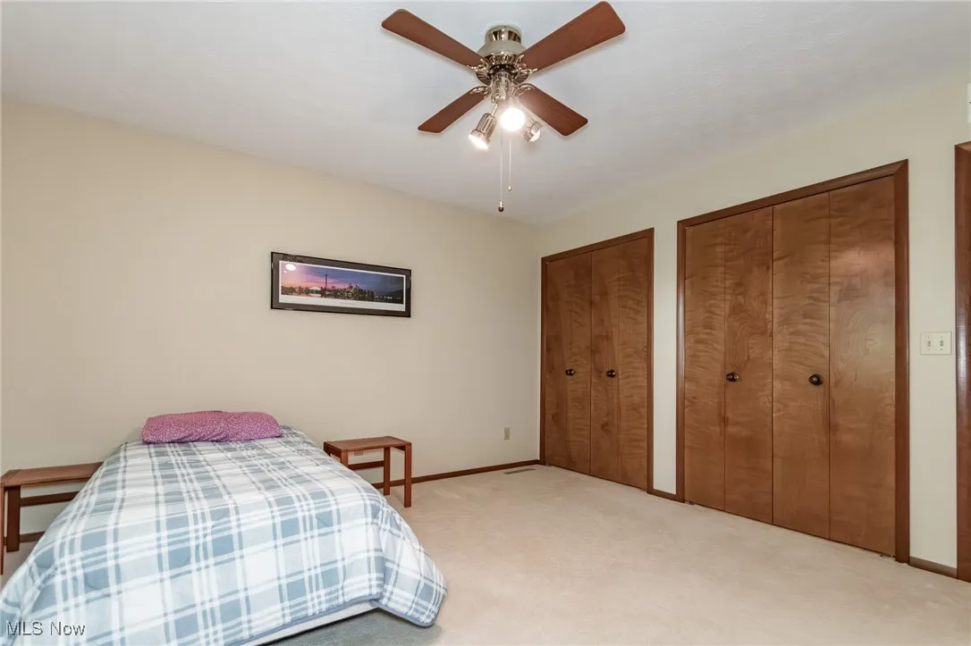 Bedroom featuring two closets, light carpet, and ceiling fan