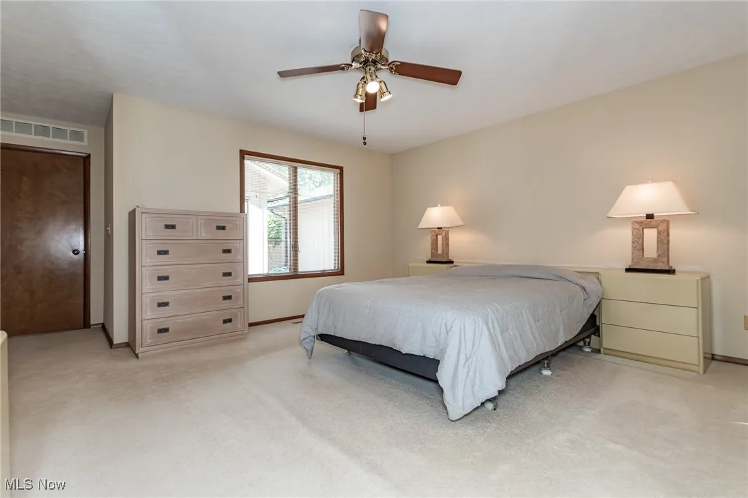Bedroom with light carpet and a ceiling fan