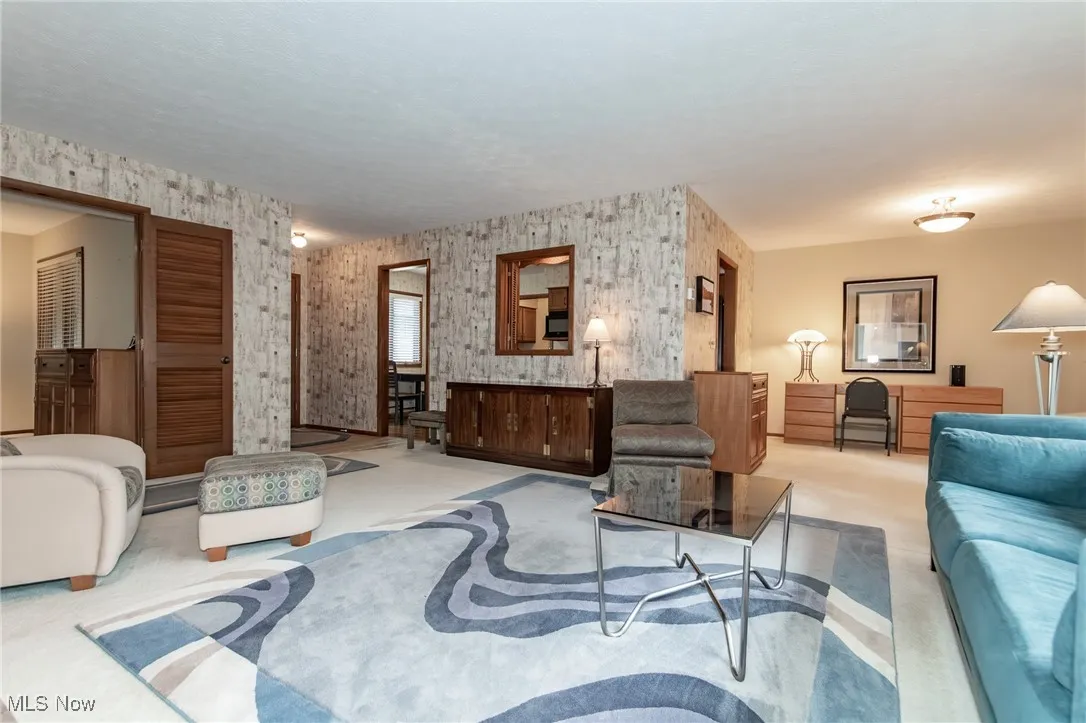 Carpeted living area with wallpapered walls