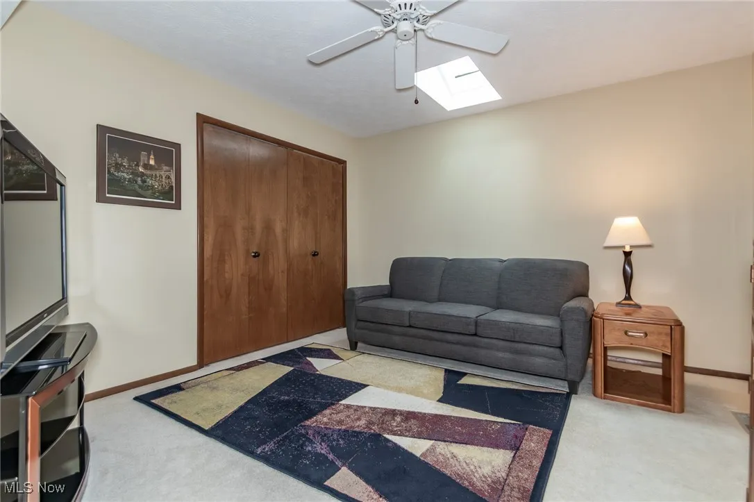 Carpeted living room featuring a skylight and ceiling fan