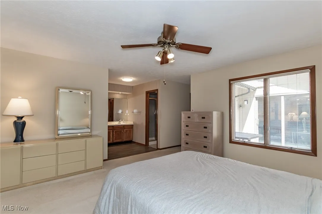 Bedroom featuring ensuite bath, a ceiling fan, and light colored carpet