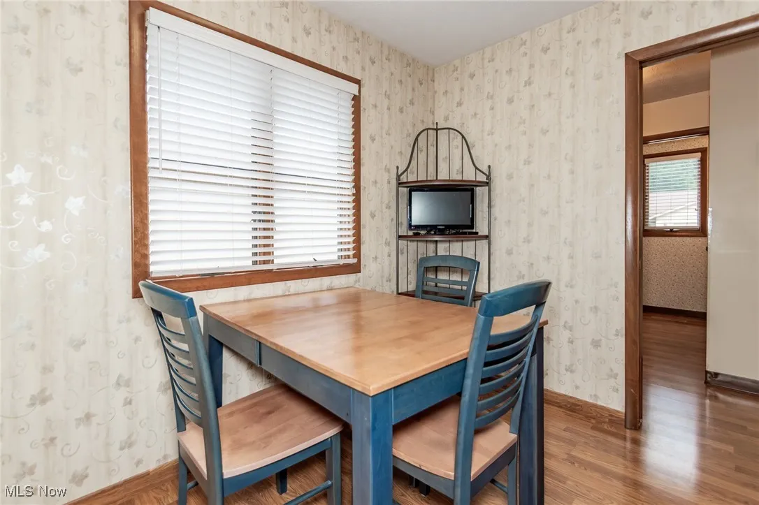 Dining area with wallpapered walls and wood finished floors