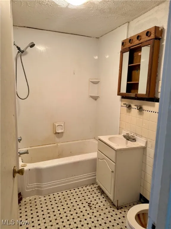 Bathroom with vanity, a textured ceiling, and washtub / shower combination