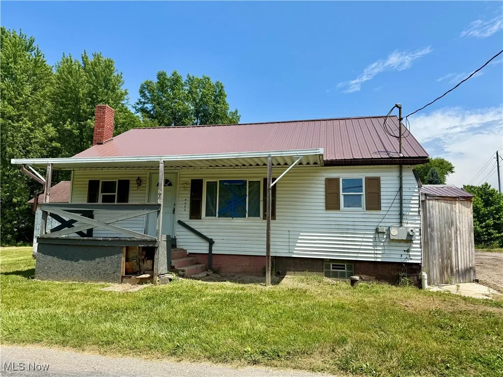 View of front facade featuring a metal roof, a front yard, and a chimney