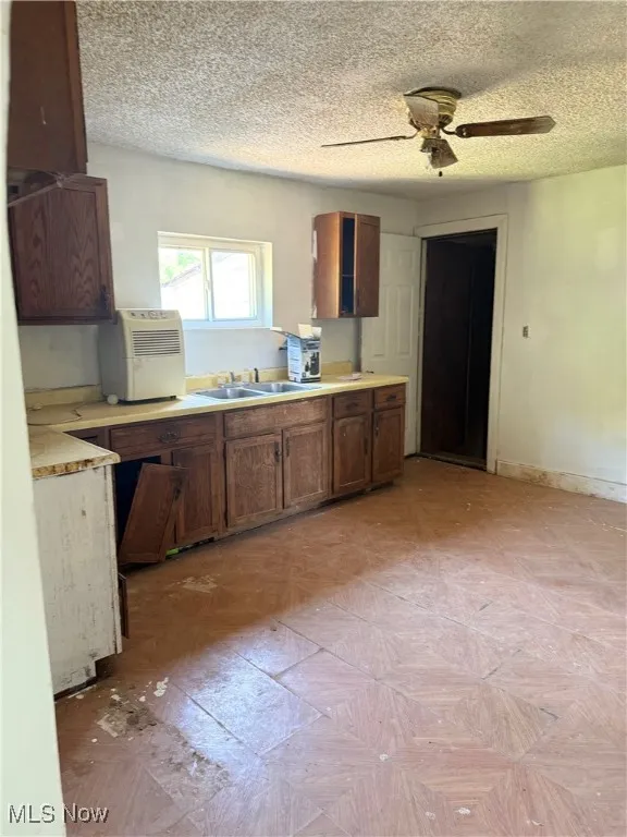 Kitchen featuring a textured ceiling, light countertops, and ceiling fan